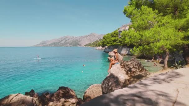 克罗地亚Brela岩石海岸迷人的女子日光浴 清澈的海水和夏日生机勃勃的生命 — 图库视频影像