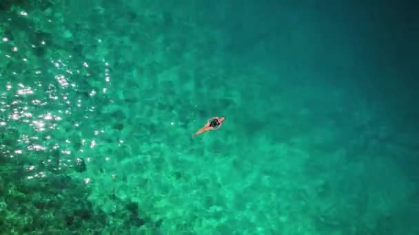 アドリア海のエメラルドの水はクロアチアのブレラの海岸から泳ぐ女性の孤独な姿を包みます — ストック動画
