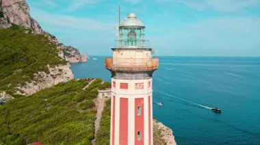 Majestic deniz feneri İtalya 'daki Capri Adası' nın sakin mavi deniz sularının üzerinde nöbet tutuyor. Denizciler için tarihi bina Faro di Punta Carena işaret fişeği..
