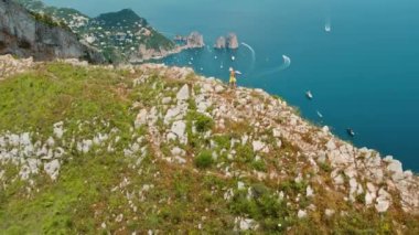 Sarı elbiseli kadın, Capri Sahili 'ne bakıyor. Gezgin, denizin ve lüks teknelerin nefes kesici manzarasını seyrediyor. İtalya 'da yaz tatilleri..