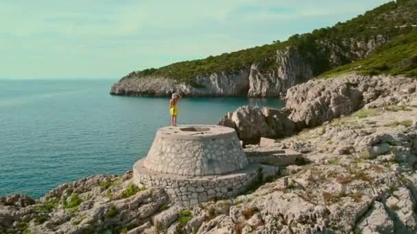Vrouw Zomerjurk Kijkt Uit Serene Blauwe Zee Rotsachtige Kust Van — Stockvideo