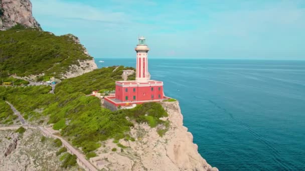 海の険しい崖に囲まれた鮮やかな赤い灯台 イタリアのカプリ島に位置するファロディプンタカレーナの航空眺め — ストック動画