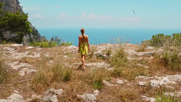 一个孤独的女徒步旅行者俯瞰着卡普里群岛 那里有岩石般的海岸线和遍布船只和游艇的第尔仁海 Faraglioni岩石 — 图库视频影像