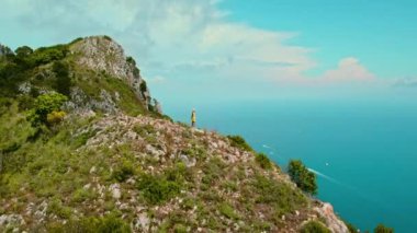 Capri Adası 'nın en yüksek noktasındaki yürüyüşçü okyanus manzarasına ve kayalık uçurumlarına hayran. Faraglioni. İtalya 'da yaz tatilleri.