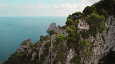 Güneş ışığı ağaçların arasından, Capri Adası 'ndan muhteşem deniz uçurumlarına ve sakin deniz sularına bakan bir kadının üzerine süzülüyor. İtalyan tatilleri..