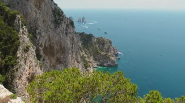 Akdeniz 'in yüksek güneşi altında Capri kıyı kayalıkları yakınlarındaki turkuaz deniz sularında tekneler iz bırakır...