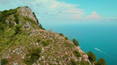 Capri sahil şeridinde kadın yürüyüşçüyüm. Denizin üstüne bakıyorum. Uçurumun tepesinden deniz manzarası seyreden bir turist. İtalya 'da yaz tatilleri..