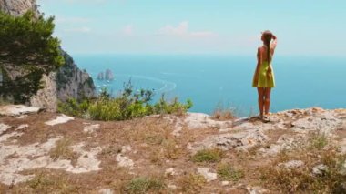 Capri Adası üzerindeki engebeli araziyi keşfeden bir turist. Yürüyüşçü, Faraglioni kayalarıyla huzur hangarına bakıyor. İtalya 'da yaz cenneti..