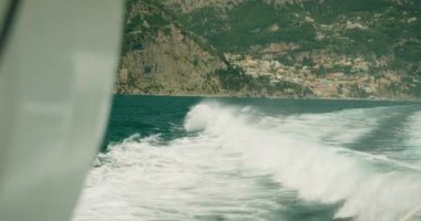 Bir sürat teknesi yaz gezisi sırasında Capri açıklarında, Marina Grande yakınlarında turkuaz deniz sularında köpüklü bir iz bırakır...
