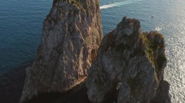 Capri 'ye bakan Faraglioni deniz yığınları, zevk teknelerindeki ziyaretçiler adanın güzelliğine dalmış panoramik deniz manzarasının tadını çıkarıyorlar...