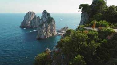 Yaz kıyafetleri içinde ziyaretçi, zengin bir uçurum bahçesinden gelen Faraglioni ile Capri Adası 'nın panoramik manzarasının keyfini çıkarın. Deniz manzaralı kadın manzarası..