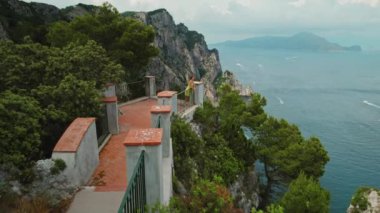 Heybetli uçurumlar sakin mavi deniz sularının üzerinde kule gibi. Capri Adası manzaralı, sakin okyanus manzaralı bir kadın. Yaz İtalya manzarası..