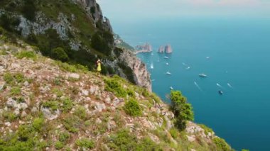 Dağlarda yürüyüş yapmak ve kayalık sahil şeridiyle Capri Adası 'nın manzaralı güzelliğini düşünmek. Uçsuz bucaksız deniz manzarasının tadını çıkaran kadın...