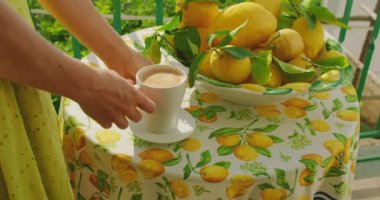 Güneş ışığı bir fincan Sabah Espresso 'sunu ve olgun limonları masada yıkıyor. Kadın güne enerji verici içecekle başlıyor. Taze Akdeniz sabahı..