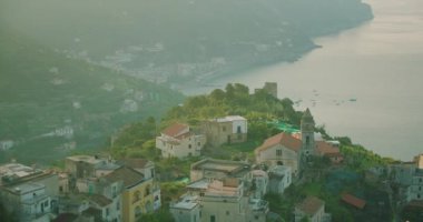 Kıyı köyü Ravello puslu bir gün doğumunda uyanır. İtalya 'da tuhaf evleri ve yeşil terasları olan deniz manzaralı...