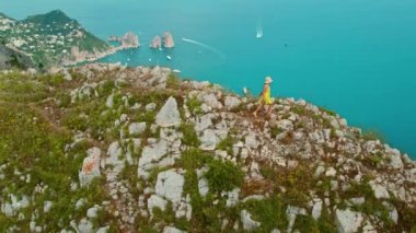 Bir dağ sırtında nefes kesici bir deniz manzarasıyla yürüyüş yapan bir kadın. Serin mavi deniz sularına ve İtalya 'nın kayalık kıyılarına bakan..
