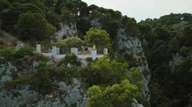 Verdant Capri Peyzajı 'nın ortasındaki nefes kesici uçurum manzarası. Huzurlu denizin üzerinde yalnızlığın tadını çıkaran rahat bir kadın...