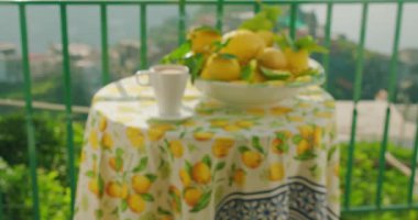 Balkondaki bir kase taze limonun yanında sabah kahvesi. Rahatlamayı davet eden kıyı kasabasının sakin panoramik manzarası..