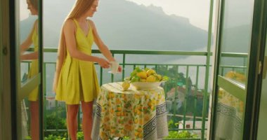 Giyinik bir kadın, sabah ayininin keyfini çıkartıyor. Bir fincan sıcak içecekle. Doğayı çevreleyince güne huzurlu bir hava katıyor...