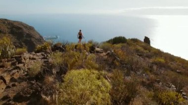 Bir yürüyüşçü Tenerife 'nin yukarısından Los Gigantes uçurumlarının ve Puerto Santiago kasabasının manzarasına hayran. Doğada doğa yürüyüşü yapan bir kadın..