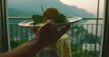 Gün batımına karşı tabakta büyük bir limon silueti. Gece çökerken garson, turunçgilleri tabakta sofraya getirir...
