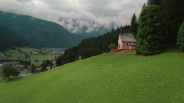 Avusturya, Gosau 'da bir tepede. Vadinin nefes kesen manzarası ve uzaktaki dağlarla birlikte insan yol boyunca koşar. Yeşil manzara ve büyüleyici alp mimarisi..
