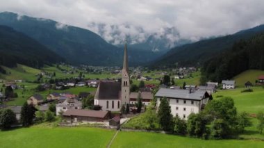 Avusturya 'nın Gosau kentinde, görkemli dağ sıraları tarafından çerçevelenmiş yemyeşil ve kırsal evler arasında yer alan sarp bir kulesi olan antika bir kilise bulunuyor...