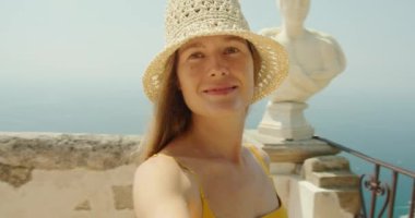 Arka planda deniz olan bir balkonda panoramik manzara gösteren gülümseyen bir kadın. Güneşli bir yaz gününde İtalya 'da kıyı şeridi..