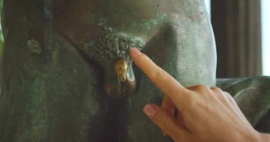 Bronz bir heykele dokunan elin yakın çekimi. Bu bir inanıştır ve turistler iyi şans ve hayallerin gerçekleşmesi için heykeli ovalarlar...
