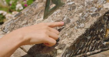 Kadınların eli, yaz bahçesindeki eski bir güneş saati ile günün saatini belirler...