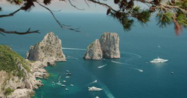 İkonik Faraglioni, Capri kıyılarında, kristal berrak Akdeniz sularında çeşitli tekne ve yatlarla çevrili...