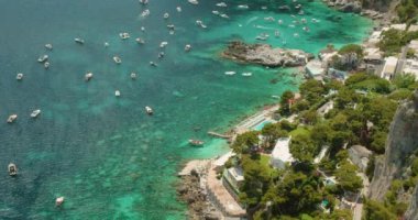 Capri Adası 'nın kıyı bölgesinde güneşli bir yaz gezisinde kristal berrak sular, tekneler ve yemyeşil alanlar sergileniyor...