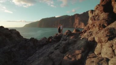 İspanya 'nın Tenerife kentindeki Los Gigantes kayalıklarının kıyısındaki kayalık arazide bir çift duruyor...