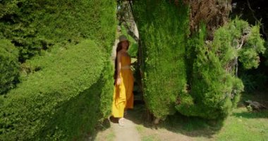 Gülümseyen kadın yaz bahçesinde uzun, manikürlü yeşil çitlerin arasında koşuyor...