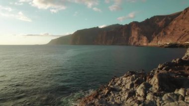 Tenerife 'deki Los Gigantes Kayalıkları' nda bir kadın ve erkek birlikte duruyorlar. Arkasında okyanus ve kayalıklar açık bir gökyüzünün altında...