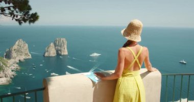 İtalya 'da Capri Adası' na bakan haritalı bir kadın. Arka planda Faraglioni deniz yığınları..