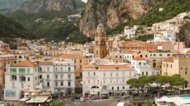 Amalfi kasabası ve ana meydanında belirgin katedral ve çevresindeki binalar ve uçurumlar yer alıyor...
