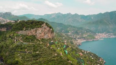 Yaz boyunca İtalya 'da yeşil tepeler, uçurumlar ve arka planda deniz manzaralı Amalfi Sahili