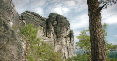 Bulutlu gökyüzüne karşı dramatik kaya oluşumları, yeşil çam ağaçları engebeli araziyi ve bölgenin doğal güzelliğini vurguluyor...