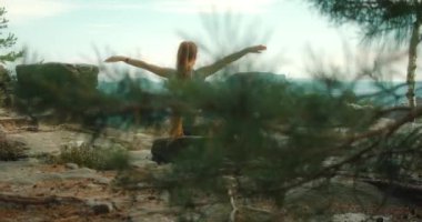 Arkasında Bastei kaya oluşumları ve ormanın engin ve sakin manzarası olan bir kayanın üzerinde meditasyon yapan bir kadın. Kız, Almanya, Sakson İsviçre 'de uçurumda yoga pozu veriyor...