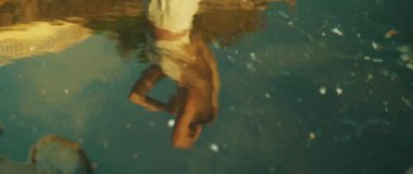 Sudaki bir kadının yansıması, eli kafasına dokunuyor. Okyanusun kıyısında saçını tarayan yetişkin bir kız...