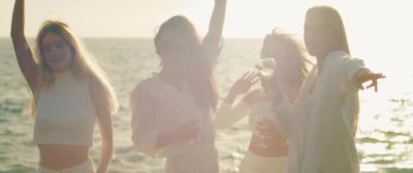 Kadınların birbirleriyle etkileşim içinde olduğu ve birbirlerinden hoşlandıkları canlı bir atmosfer, arka planda ışıldayan okyanus tarafından çerçevelenmiş...