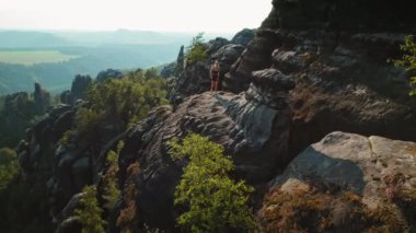 Schrammsteine Elbe Kum Taşı Dağları 'nda ağaçlar ve kaya oluşumlarıyla tek başına yürüyen bir kadın..