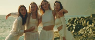 Yumuşak ışık altında birbirine sarılan dört kadın, denizin arka planında ve uçurumlarda. Los Gigantes Tenerife Kanarya Adaları İspanya..