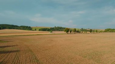 Yuvarlanan tepeleri, sıra sıra ağaçları ve uzaktan çalışan yalnız bir traktörü olan ekilmiş tarım arazisi...