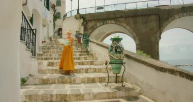 Bir kadın elinde haritayla İtalya 'nın kıyı köyünde taş merdivenlerden aşağı iniyor..