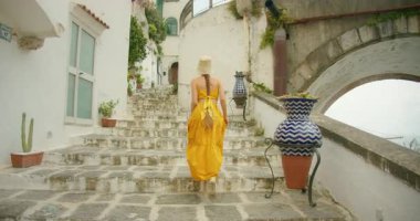 Amalfi kıyısındaki İtalyan sahil kasabası Atrani 'deki eski taş merdivenlerden çıkan kadın kemer yolunun altında..