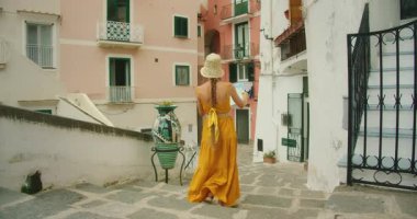 İtalya 'nın Atrani şehrinde renkli binalarla dar bir sokakta yürüyen genç bir kadın..