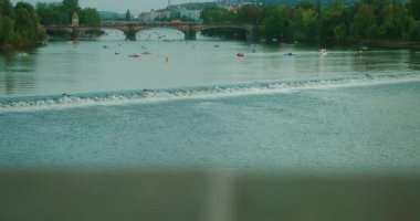 Prag 'daki Vltava Nehri manzaralı, arka planda tarihi bir köprü ve kürek tekneleriyle dolu..