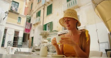 Atrani Meydanı 'ndaki açık bir kafede kahve içen bir kadın..